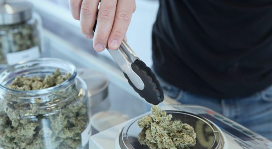 A man is weighing out cannabis onto a scale in a dispensary