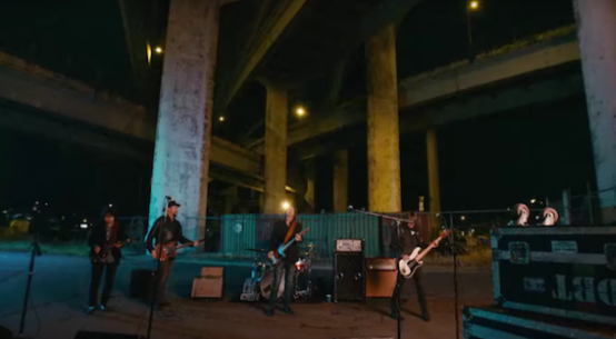 The Drive By Truckers stand beneath a freeway overpass playing their instruments