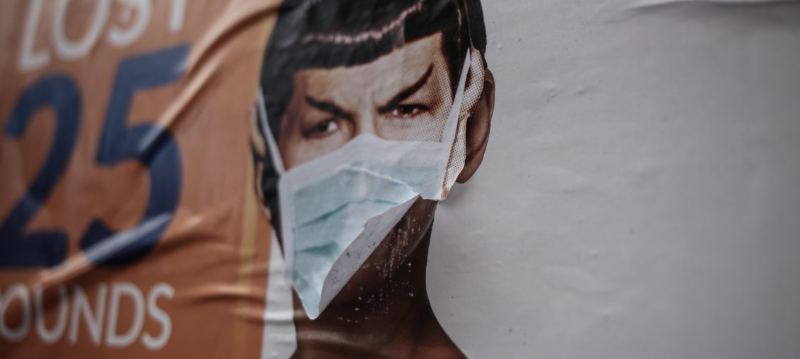 A mural of the character Spock from Star Trek has a surgical mask someone has attached which is fluttering in the breeze.